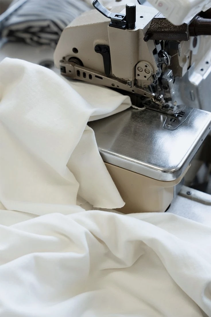 An industrial overlock sewing machine assembling side panels on a heavy fleece streetwear hoodie