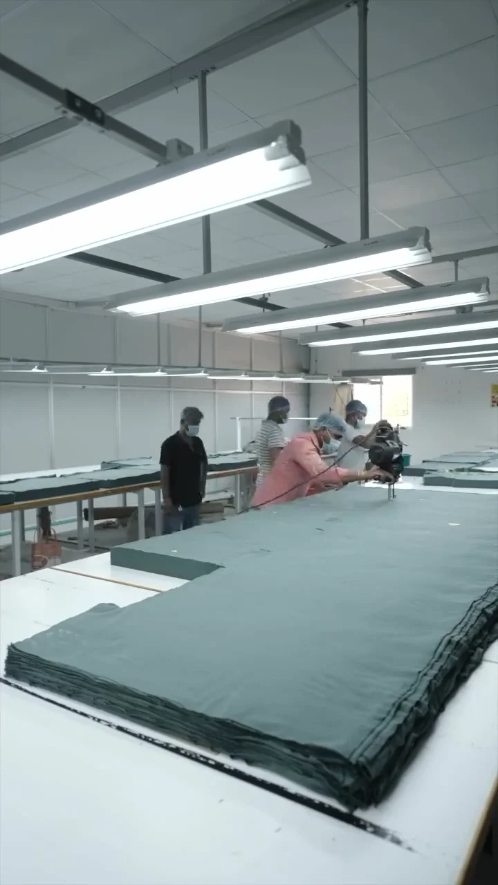 A master pattern cutting professional slicing layers of apparel fabric on a long industrial cutting table