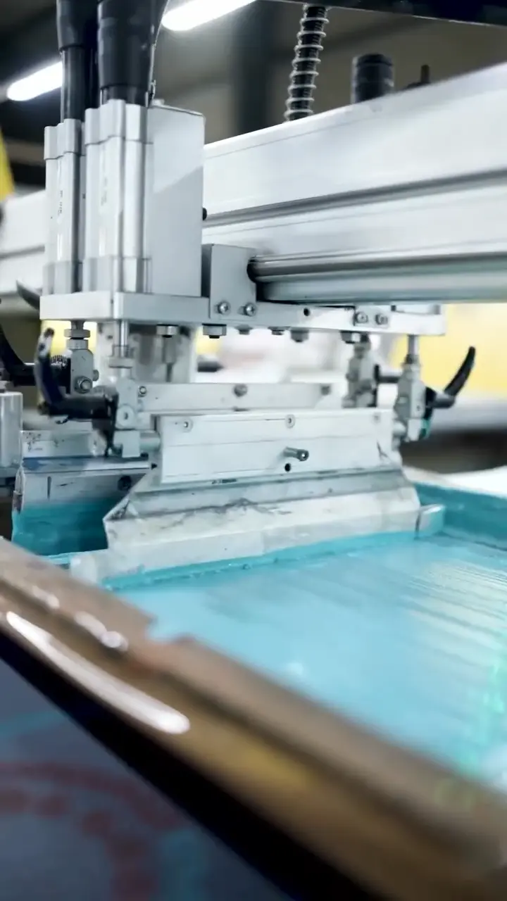Close-up view of an automated carousel textile screen printing machine head filled with plastisol ink