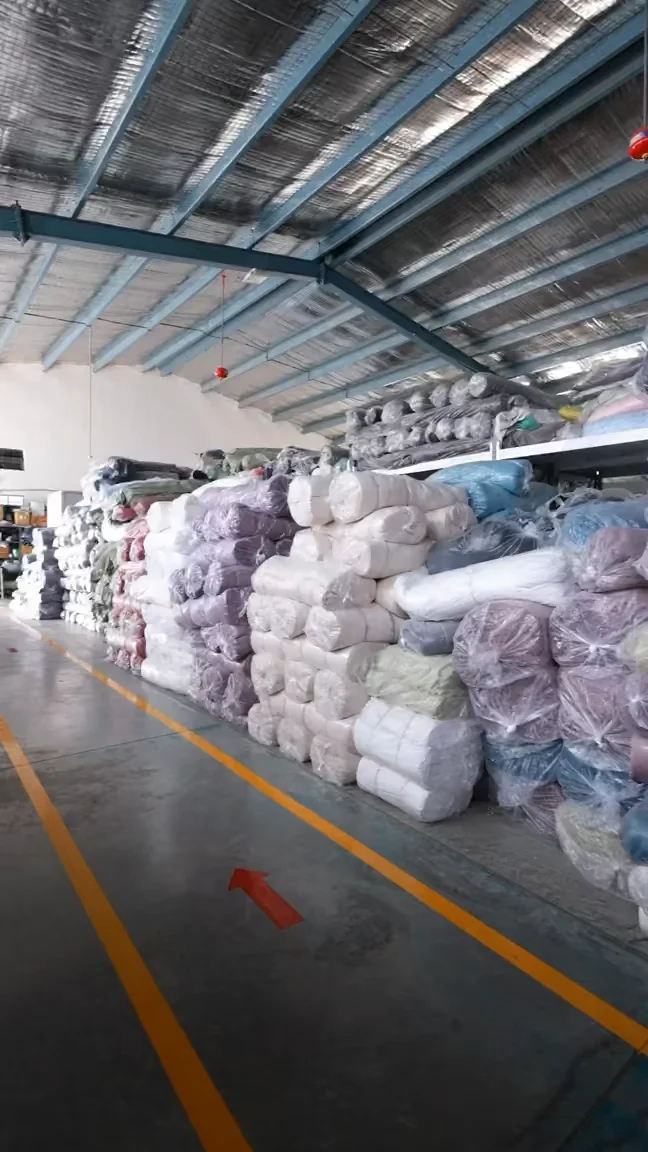 An organized inventory corner inside the factory storing premium raw clothing fabric rolls