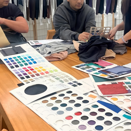 Factory production team reviewing a client design blueprint and detailing garment technical requirements