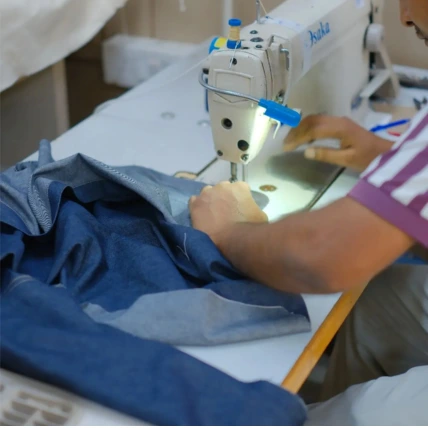 Skilled operators executing mass production apparel assembly using specialized high speed stitching machinery